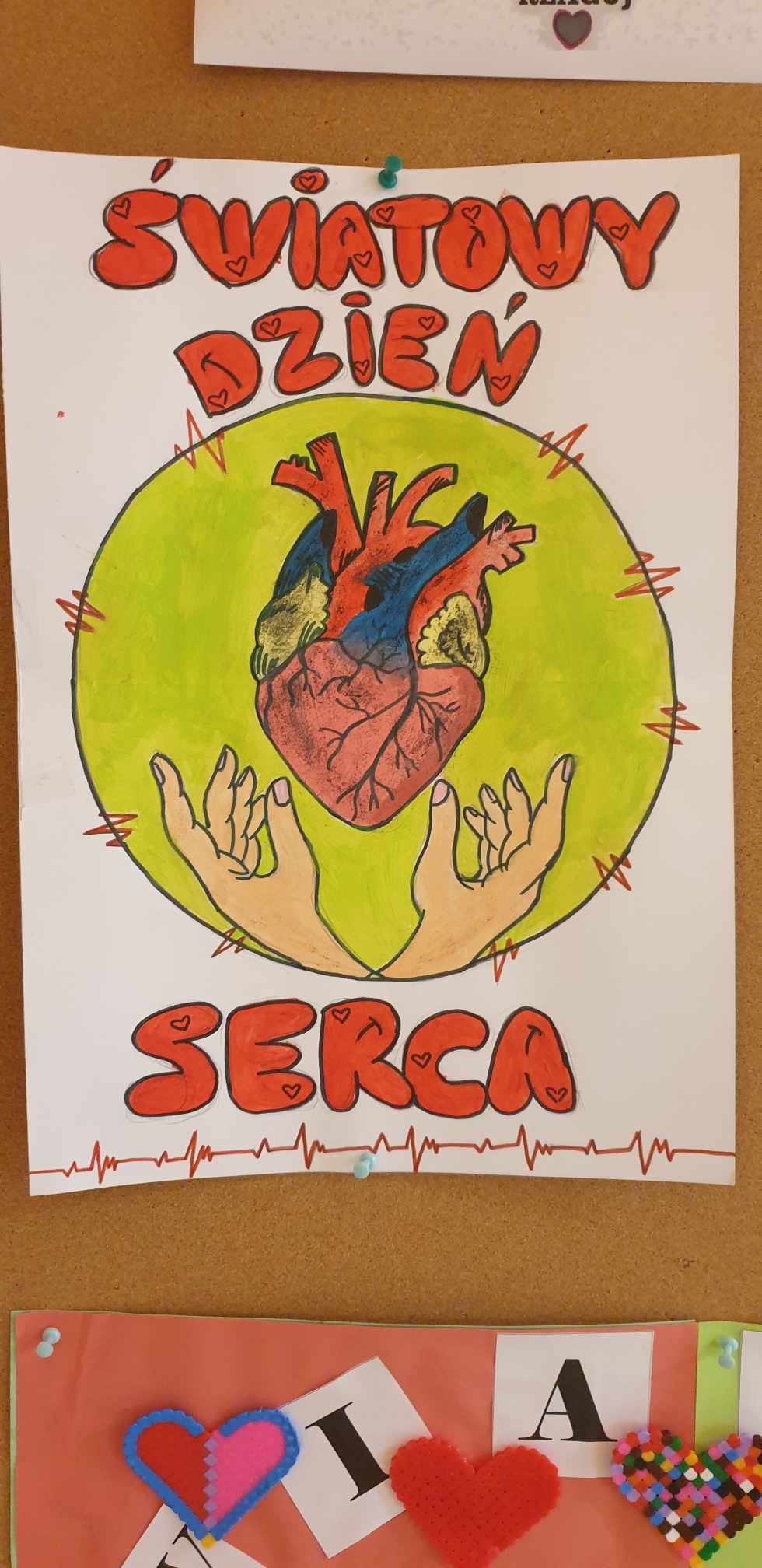 Plakat światowego dnia serca: serce w żółtym kole, pod nim dłonie.