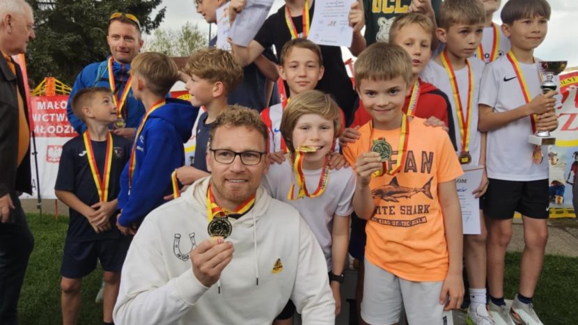 drużyna chłopców wraz z trenerem i z zawieszonymi na szyjach złotymi medalami