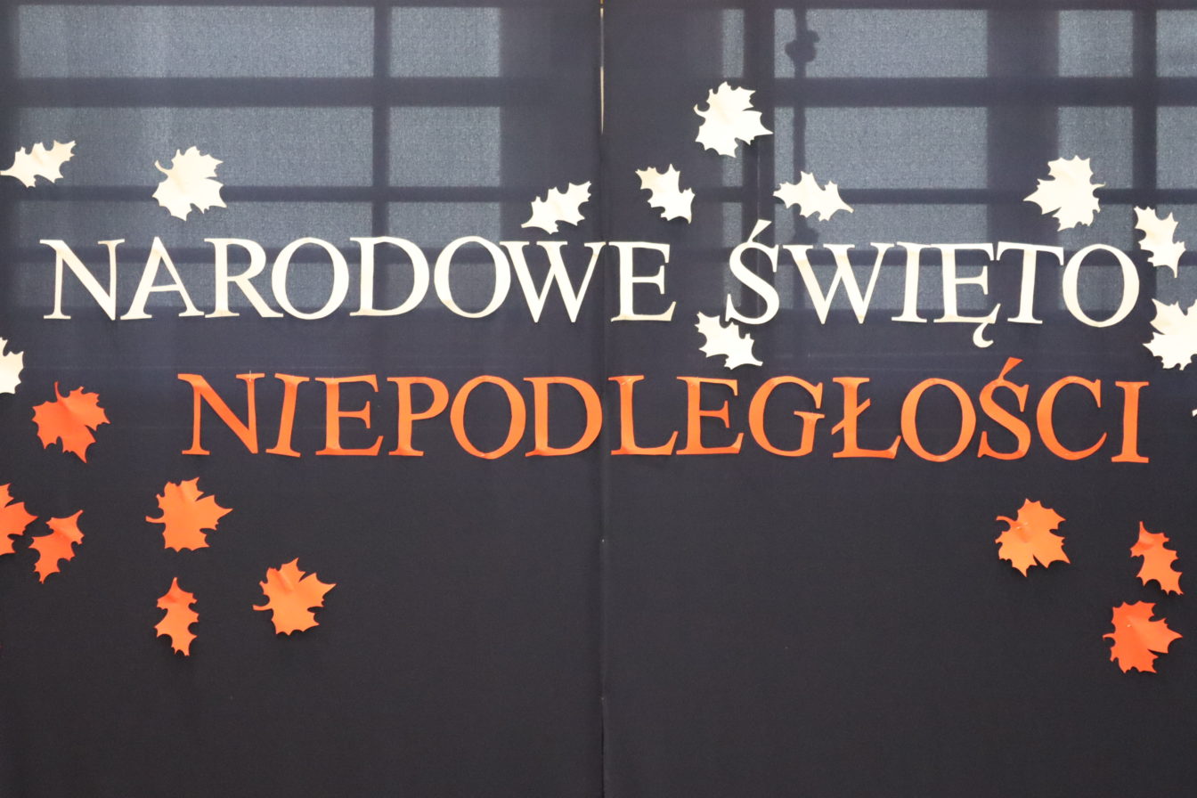 Napis NARODOWE ŚWIETO NIEPODLEGŁOSCI na granatowym płótnie przyozdobiony jesiennymi liśćmi