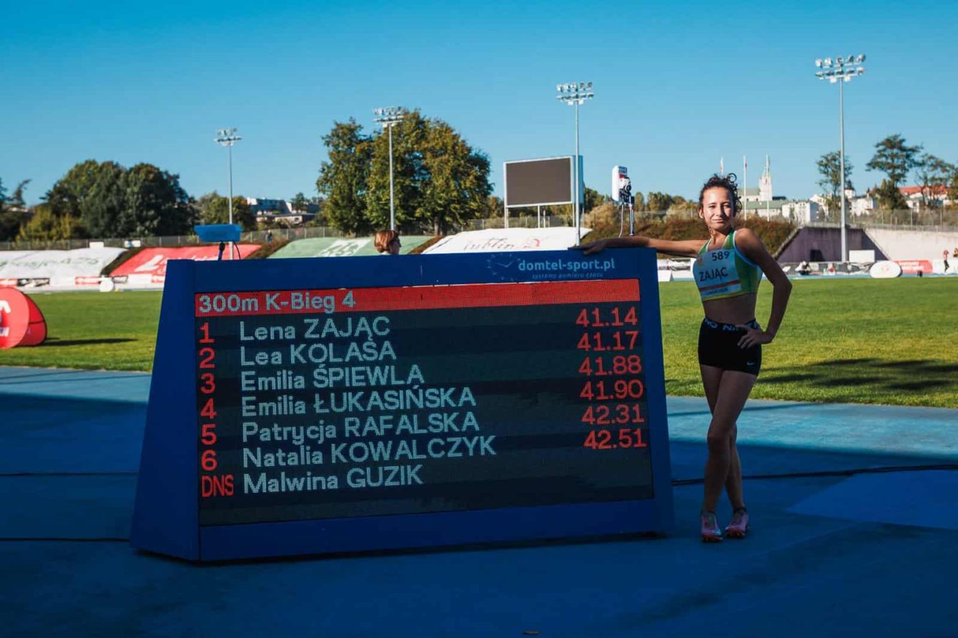 Uczennica obok zegara z wyświetlanymi czasami biegu