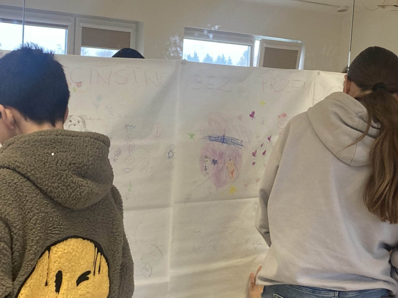 Dwóch uczniów rysuje na wielkiej kartce przyklejonej do luster (mural) w ramach akcji Dzieciństwo Bez Przemocy