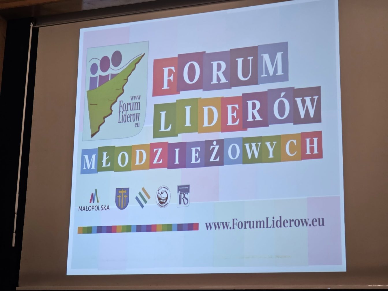 Duzy kolorowy napis wyświetlany na ekranie: FORUM LIDERÓW MŁODZIEZOWYCH