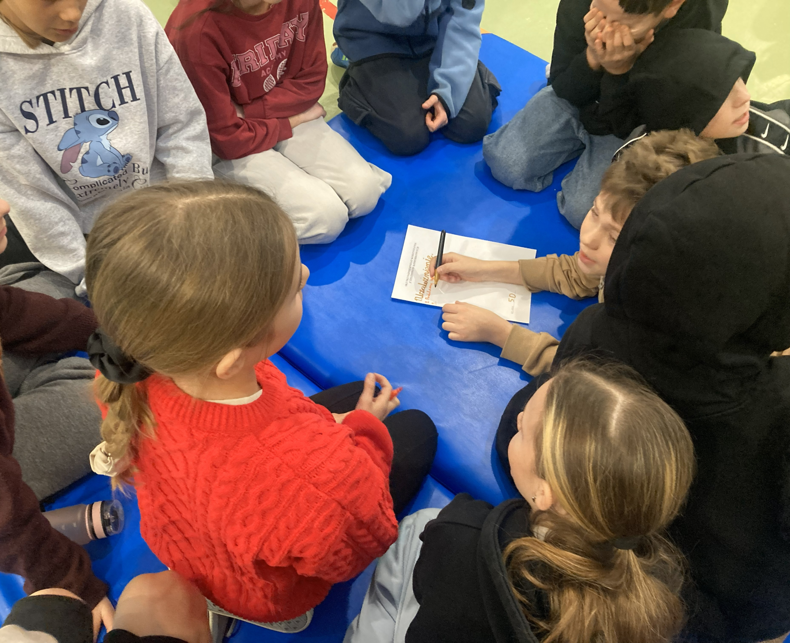 Uczniowie-siedzacy-na-materacu-i-pracujacy-w-grupie-podczas-warsztatow-dotyczacych-fonoholizmu-