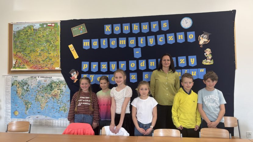 Uczniowie klas III SPnr4 wraz z Panią wicedyrektor na tle dekoracji przygotowanej na Szkolny Konkurs Matematyczno-Przyrodniczy „Jeden z siedmiu”.