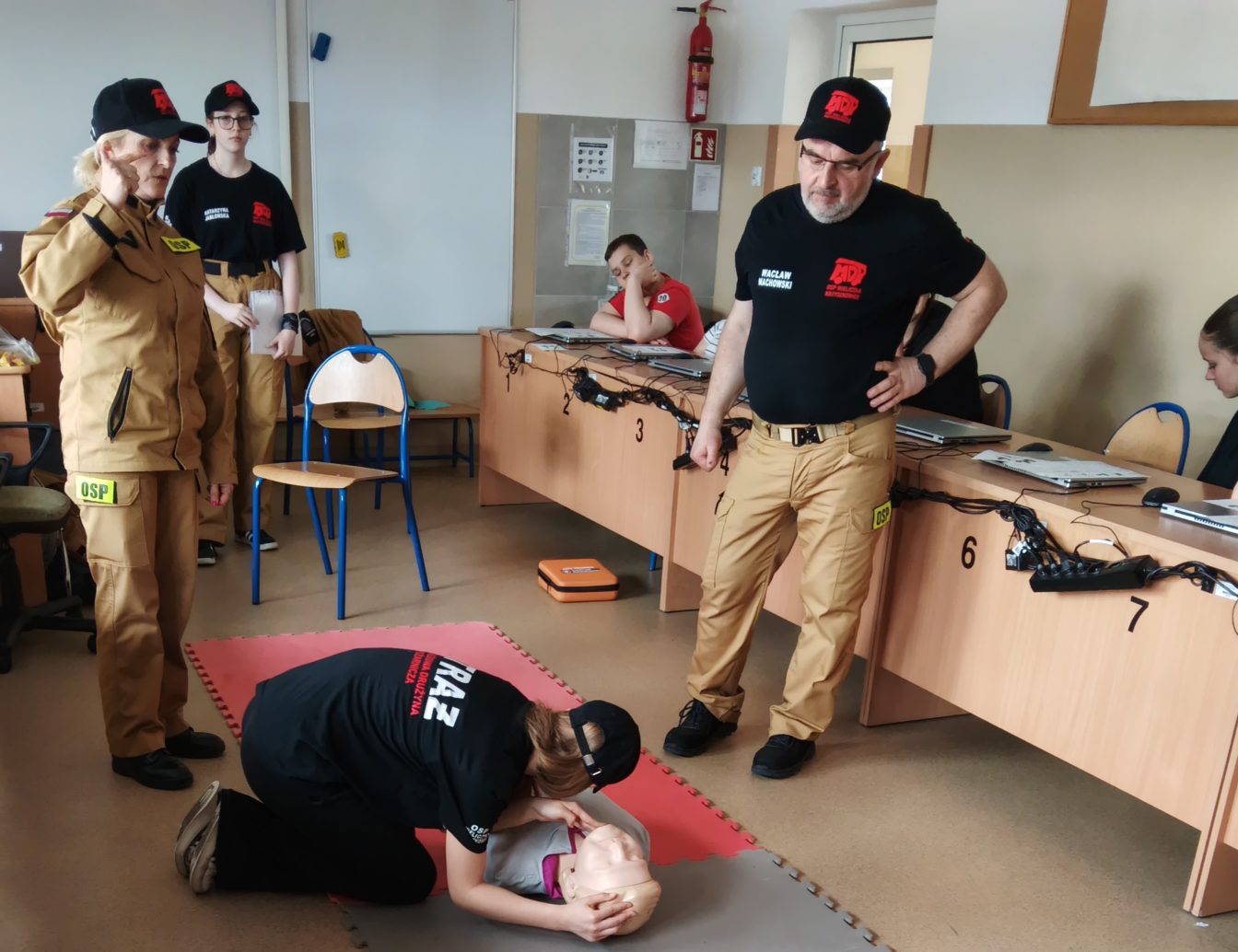 Grupa strażaków pokazuje udzielanie I pomocy podczas leckji w SP4 Wieliczka