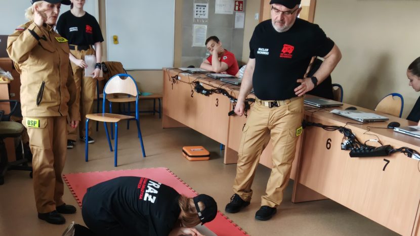 Grupa strażaków pokazuje udzielanie I pomocy podczas lekcji w SP4 Wieliczka