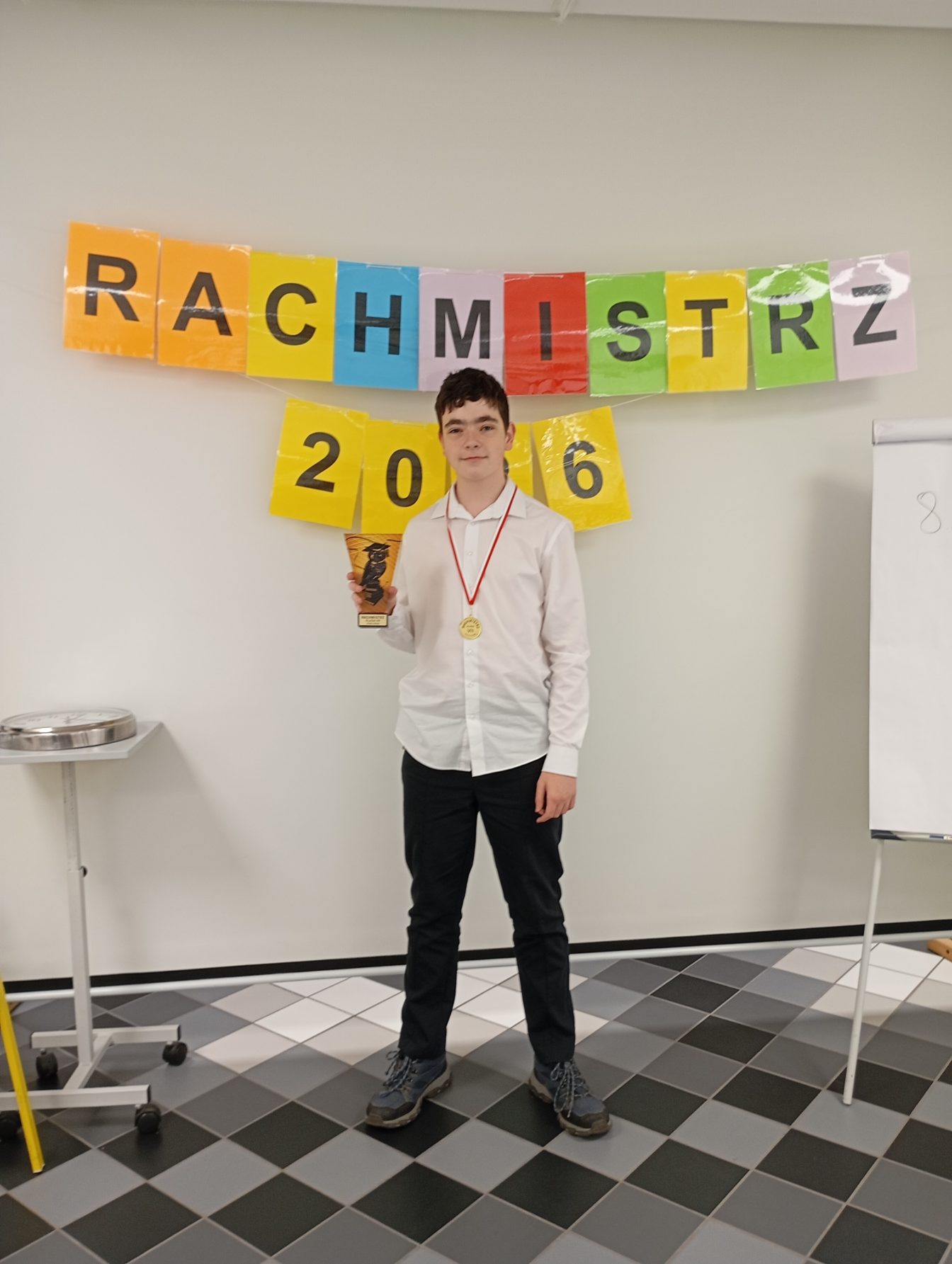 Uczeń Jaromir ze statuetką w tle napis RACHMISTRZ 2026